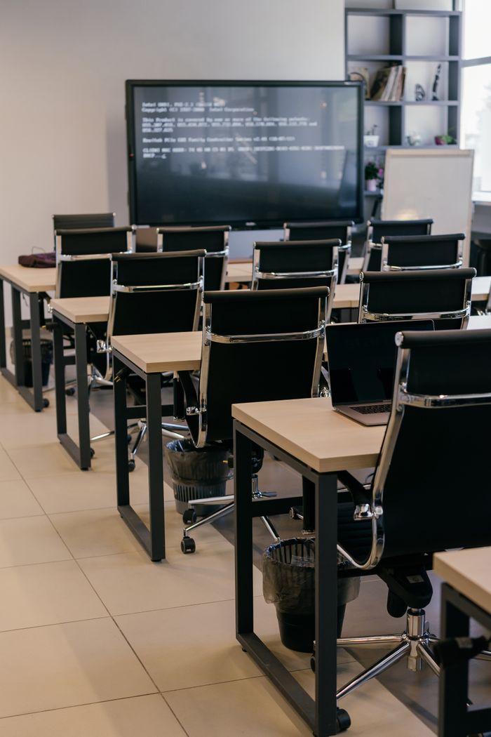 about-us Contemporary office space with sleek black leather chairs and a large screen for presentations.